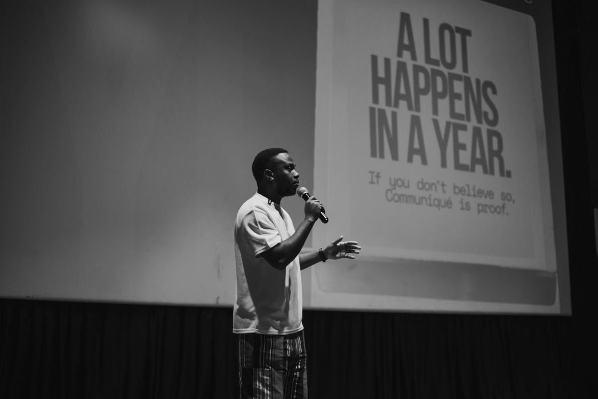 David on stage with a microphone in front of a slide that reads: A lot happens in a year. If you don’t believe so, Communiqué is proof.